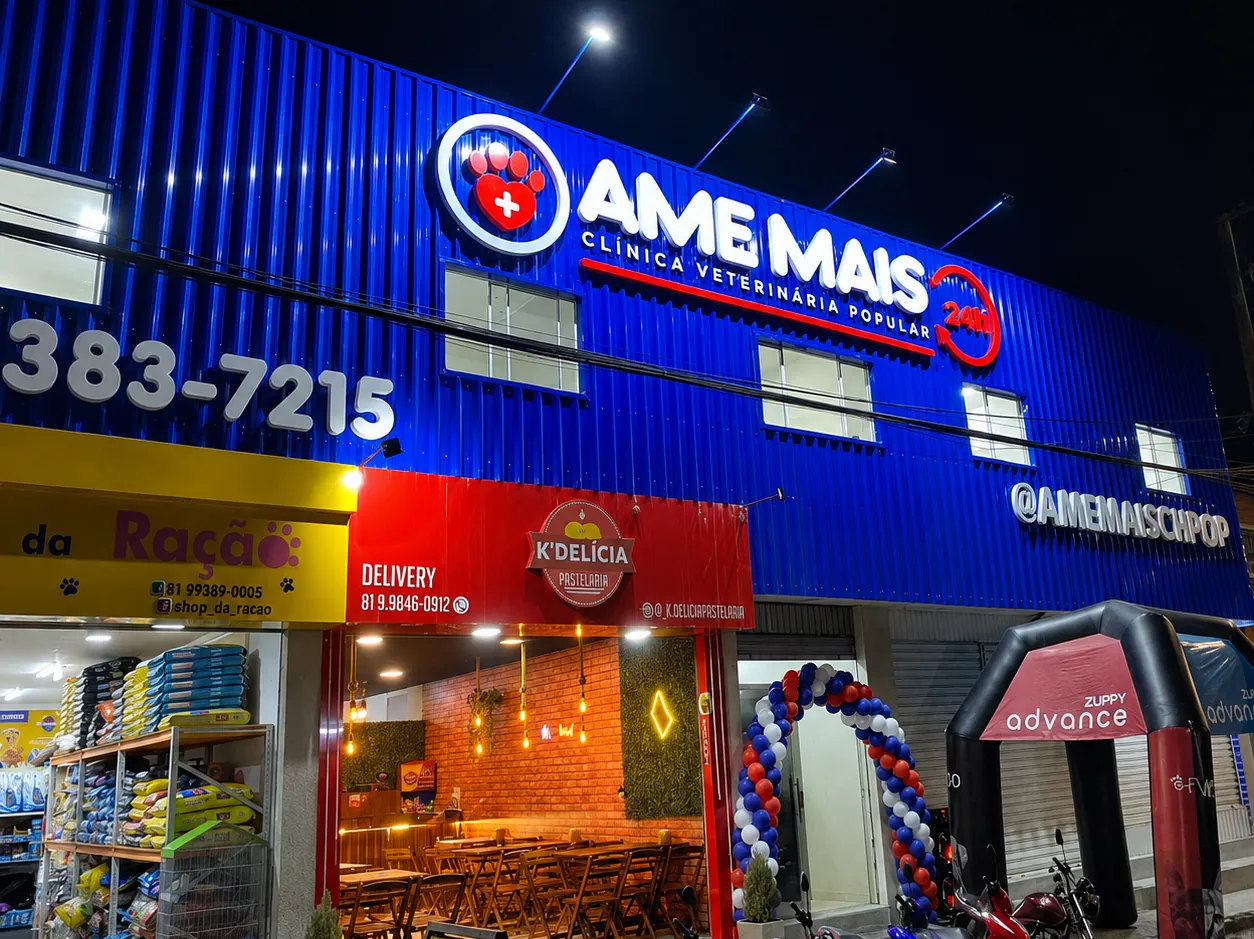 Fachada azul da Ame Mais Clínica Veterinária Popular iluminada à noite em Caruaru