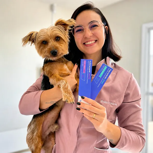Profissional da Ame Mais sorrindo com cãozinho yorkshire no colo